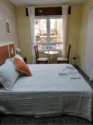 a bedroom with a large bed and a table and a window at Cuatro Caminos in Sarria