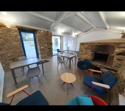 a room with chairs and tables and a stone fireplace at A Casa do Lado in Melide