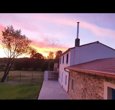 a building with a sunset in the background at A Casa do Lado in Melide
