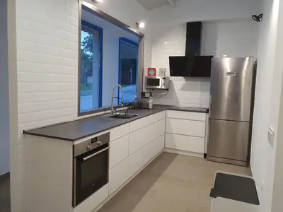 a kitchen with a stainless steel refrigerator and white cabinets at A Casa do Lado in Melide