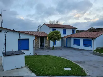 a house with blue doors and a yard at A Casa do Lado in Melide