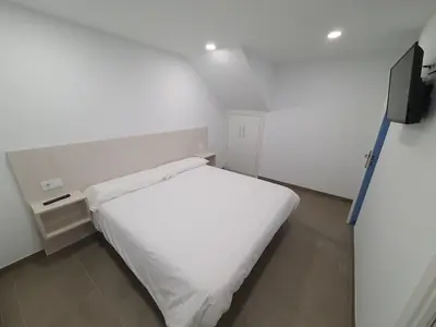 a small bedroom with a white bed and a television at A Casa do Lado in Melide