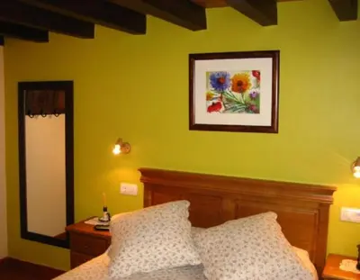 a yellow bedroom with a bed and a mirror at Apartamentos Rurales Romallande in Puerto de Vega