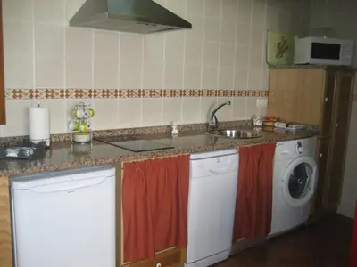 a kitchen with a sink and a washing machine at Apartamentos Rurales Romallande in Puerto de Vega