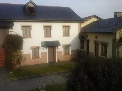 a large white house with a black roof at Apartamentos Rurales Romallande in Puerto de Vega