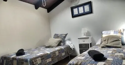 a bedroom with two beds and a table and a window at Casa Das Airas in Sarria