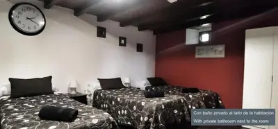 two beds in a room with a clock on the wall at Casa Das Airas in Sarria