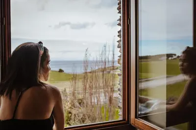 a woman looking out a window at the ocean at Hotel Pleamar in Puerto de Vega