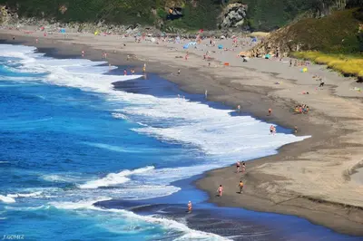 a group of people on a beach near the water at Hotel Pleamar in Puerto de Vega