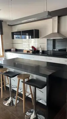a kitchen with a large black counter with bar stools at Casa JyM Fontela 24 in O Pedrouzo