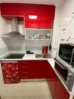 a kitchen with red cabinets and a sink at Apartamento Centro Frente Muralla 2 in Lugo