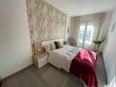 a bedroom with a bed and a wall with wallpaper at Precioso piso en el centro de Galicia. in Silleda