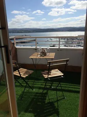 a table and chairs on a balcony with a boat at Attic loft to wake up by the sea. in Sada