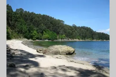 a beach with a large rock in the water at Attic loft to wake up by the sea. in Sada