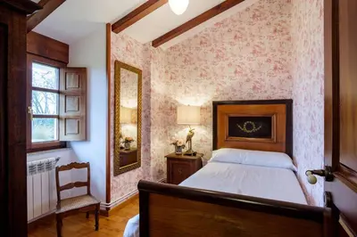 a bedroom with a bed and a chair and a mirror at Aldea A Paínza in Arzúa