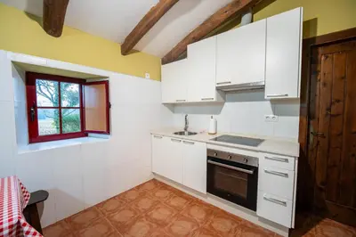 a kitchen with white cabinets and a window at Aldea A Paínza in Arzúa