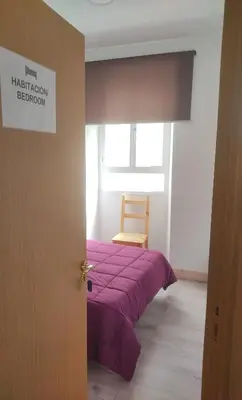 a bedroom with a purple bed and a wooden chair at Albergue Santos in Santiago de Compostela