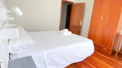 a bedroom with a white bed with a lamp and a door at Apartamentos Pantón Ribeira Sacra in Ferreira de Panton