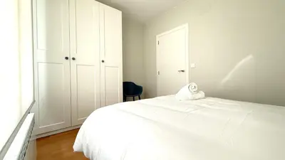 a white bedroom with a white bed and a chair at Apartamentos Pantón Ribeira Sacra in Ferreira de Panton