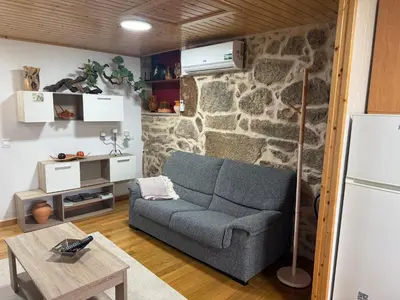 a living room with a couch and a stone wall at Casa Cerralleiro. Casa vacacional en Parada de Sil. Ribeira Sacra. in Parada del Sil