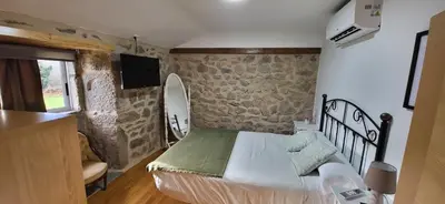 a bedroom with a bed and a stone wall at Casa Cerralleiro. Casa vacacional en Parada de Sil. Ribeira Sacra. in Parada del Sil