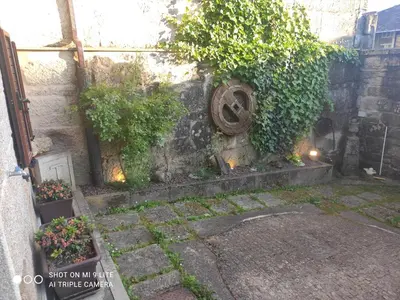 a stone wall with plants and flowers next to a building at CASA BOREAL in Ourense