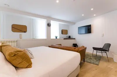 a bedroom with a bed and a chair and a television at SEIS ALDABAS Apartamentos in Santiago de Compostela
