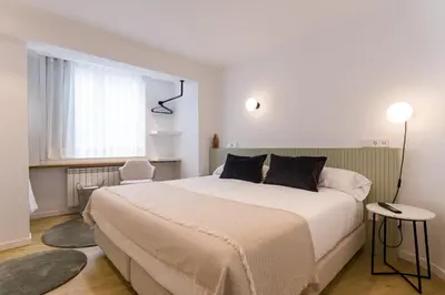 a white bedroom with a large bed and a window at SEIS ALDABAS Apartamentos in Santiago de Compostela