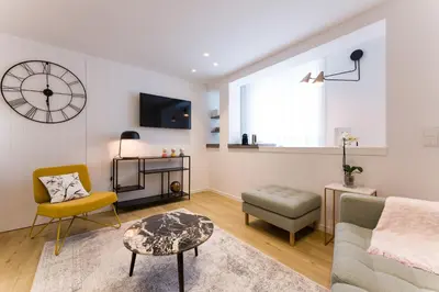 a living room with a couch and a chair and a clock at SEIS ALDABAS Apartamentos in Santiago de Compostela