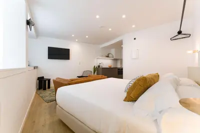 a white bedroom with a large bed and a television at SEIS ALDABAS Apartamentos in Santiago de Compostela