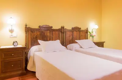 a bedroom with two beds and a wooden headboard at Casa Gayón in Pola de Allande