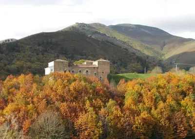 an old castle on top of a hill with trees at Casa Gayón in Pola de Allande