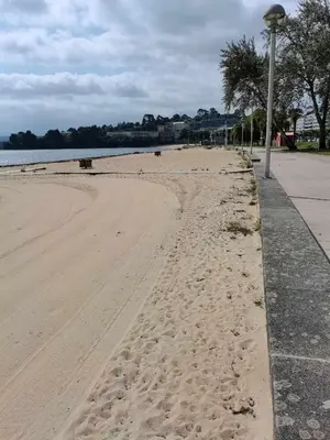 a sandy beach with a street light next to the water at Apartamento Carreira Sada in Sada
