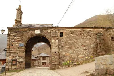 an old stone building with an arch in a street at Casa Rural La Torre De Babel in Molinaseca