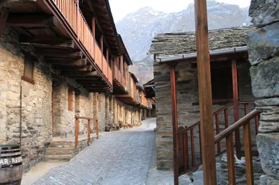 an alley in a stone building with mountains in the background at Casa Rural La Torre De Babel in Molinaseca