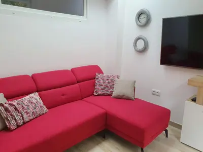 a red couch in a living room with a tv at Acogedor apartamento en el centro de Monforte in Monforte de Lemos
