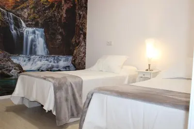 two beds in a room with a waterfall painting on the wall at Acogedor apartamento en el centro de Monforte in Monforte de Lemos