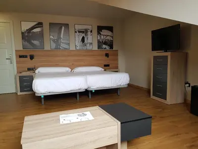 a bedroom with two beds and a table and a tv at Apartamentos Turísticos y Habitaciones Cidade Vella by Bossh! Hotels in Ourense
