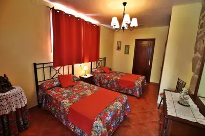 two beds in a room with red curtains at Casa de Padrón in Padrón