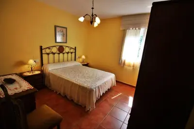a bedroom with a bed and a chair and a window at Casa de Padrón in Padrón