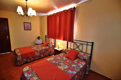 a bedroom with two beds and a red curtain at Casa de Padrón in Padrón