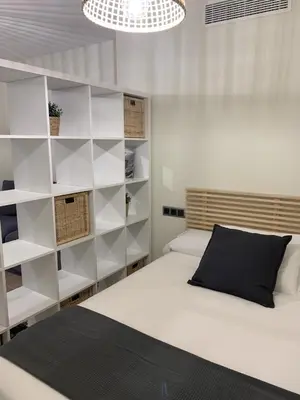 a bedroom with white shelves and a bed with a black pillow at Apartamentos San Lazaro in Santiago de Compostela