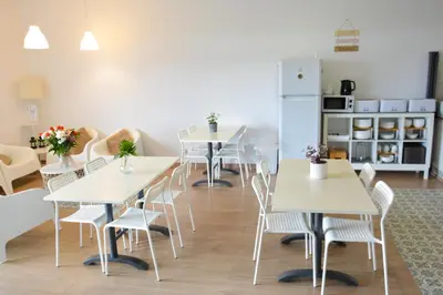 a room with tables and chairs and a refrigerator at Albergue Melide in Melide