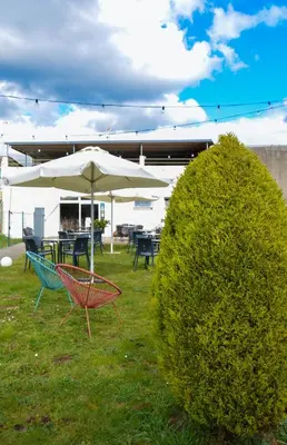 a couple of chairs and an umbrella in the grass at Albergue Melide in Melide