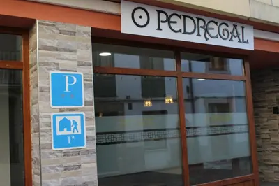 a red hospital building with a sign on the door at Pensión Albergue O Pedregal in Lourenzá