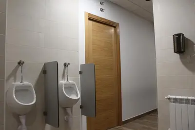 a bathroom with two urinals and a door at Pensión Albergue O Pedregal in Lourenzá