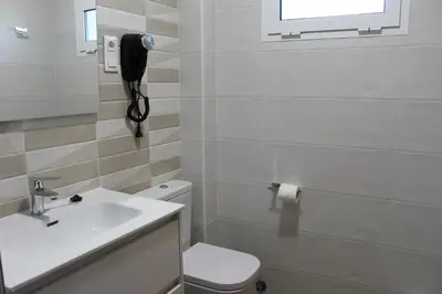 a bathroom with a sink and a toilet and a phone at Pensión Albergue O Pedregal in Lourenzá