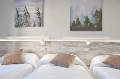 a living room with white couches and paintings on the wall at Peregrina Pension 3 in O Pedrouzo