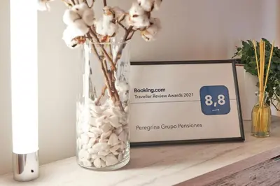 a vase with white flowers on a table next to a sign at Peregrina Pension 3 in O Pedrouzo