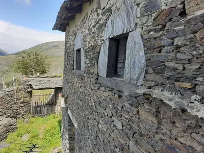 a stone building with two windows on the side of it at Albergue ESCANLAR in Lugo